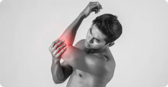 Man experiencing joint discomfort in his elbow, highlighting the need for systematic inflammation modulation through SoftWave treatments.