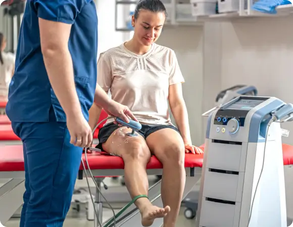 Tampa clinician performing SoftWave Therapy on a female athlete’s leg to accelerate athletic recovery and relieve delayed-onset muscle soreness.
